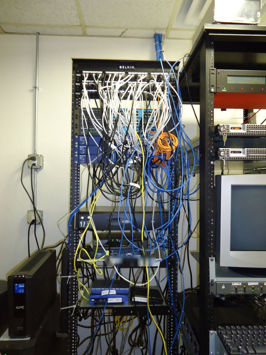 Network rack before the rewire, with tangled patch cables hanging across the switches