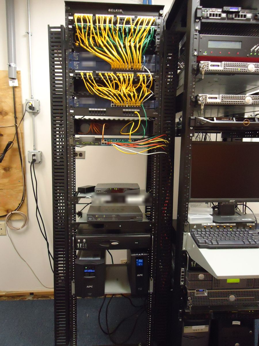 The same rack after rewiring, with short yellow and green patch cables running neatly to the switches